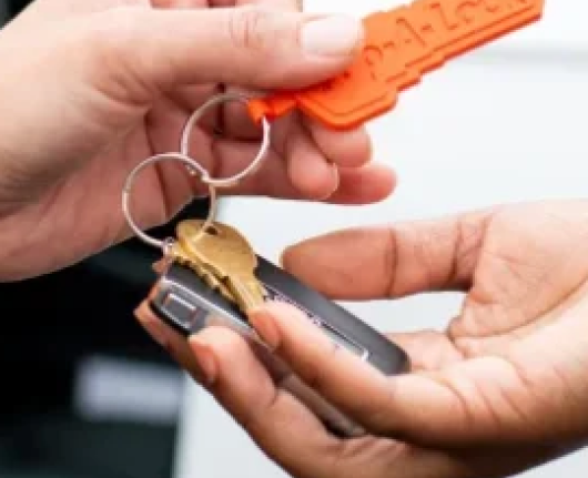 locksmith handing over a set of keys with a Pop-A-Lock Baton Rouge keychain