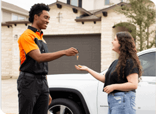 Locksmith hands keys to customer next to white car.
