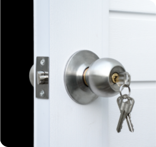 Keys in silver doorknob lock on white door.